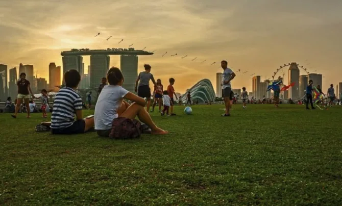 Crowds on the Marina Barrage green roof at sunset with the Singapore skyline, Marina Bay Sands, and Singapore Flyer in view